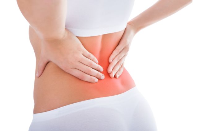 腰に手を当てて痛みを感じている女性の後ろ姿（腰痛）