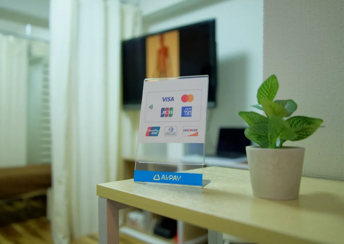 六本木の整体サロン「モビリティ整体ソシオ」で利用できるキャッシュレス決済案内。各種クレジットカードやPayPayなどで支払いが可能で、受付カウンターにAirPAYの決済案内が置かれている様子。