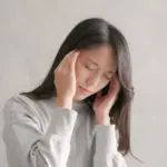 首や肩のこりが原因で頭痛に悩む六本木の整体を探す女性