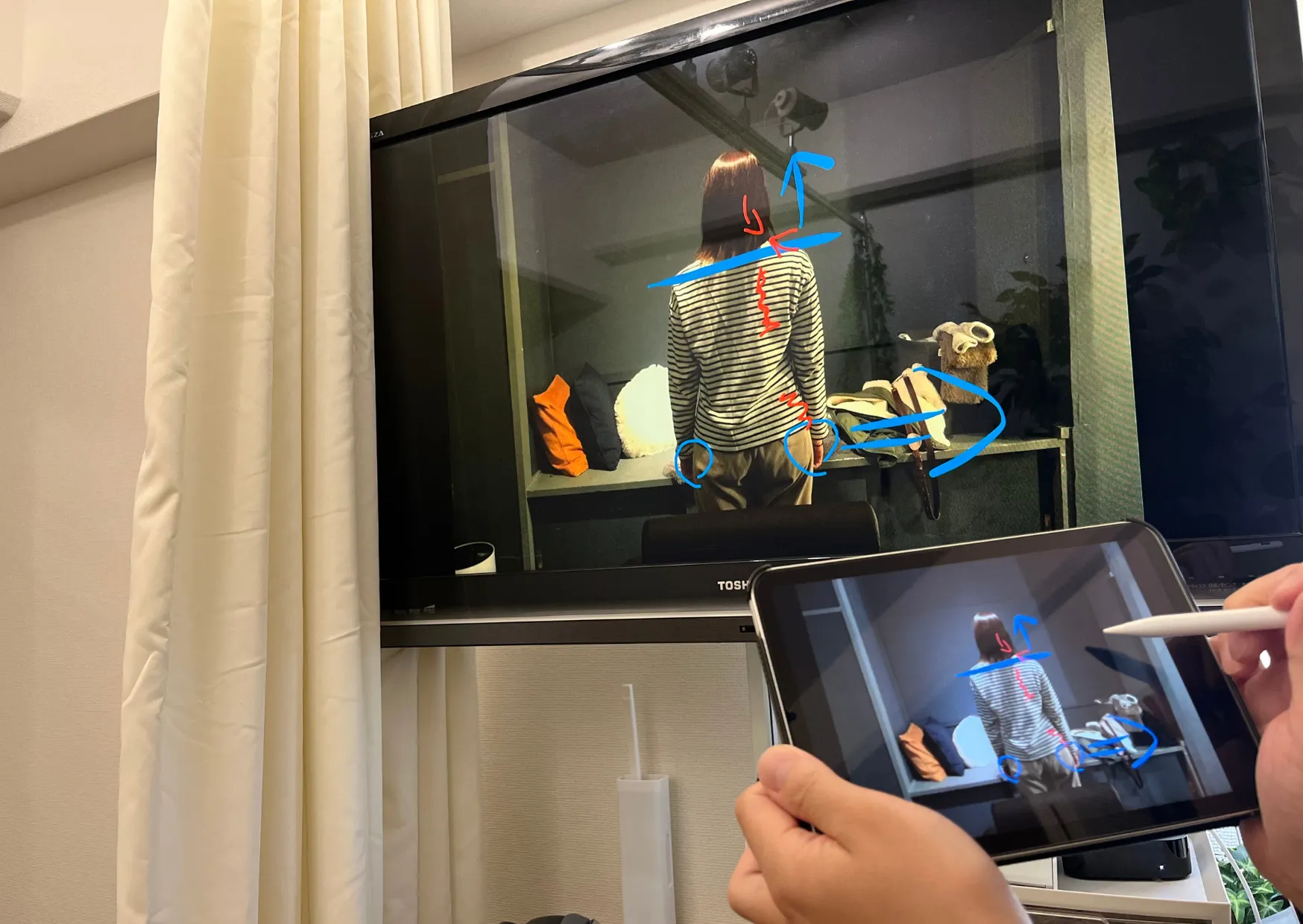 六本木の整体で患者様の姿勢写真にタブレットで線を書き込み、モニターに映して説明する様子