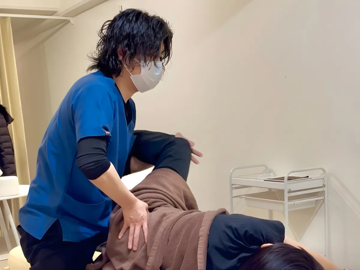 六本木の整体で患者様の股関節まわりを施術する柔道整復師