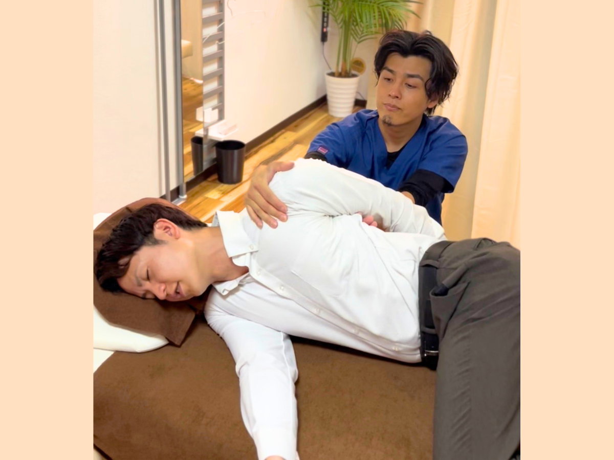 六本木の整体で横向きの患者様の背中と肩甲骨まわりを整える柔道整復師