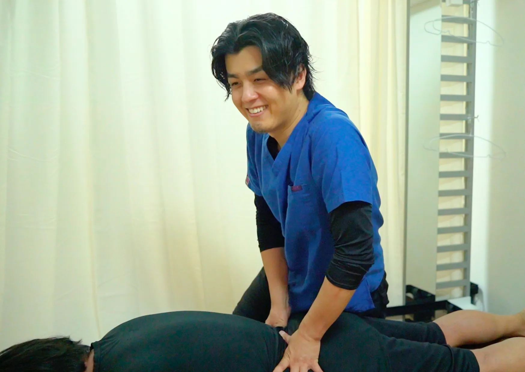 六本木の整体でうつ伏せの患者様の背中に施術する柔道整復師